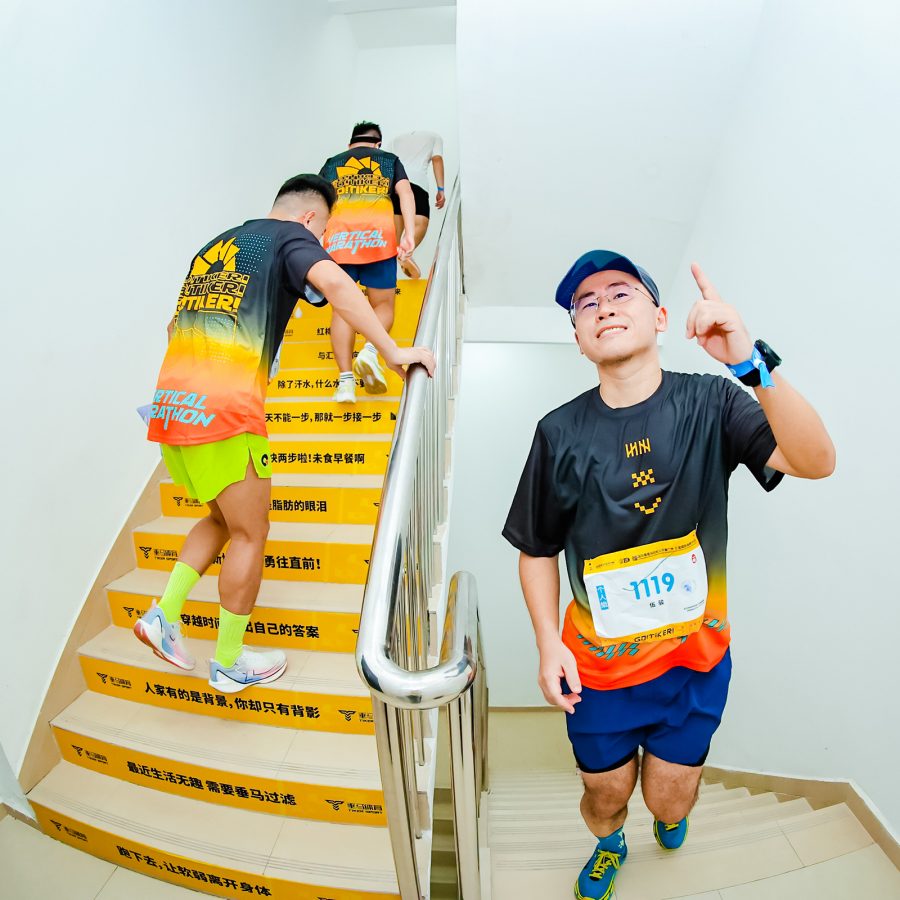 Three competitors walk up the stairs and flash a number one sign at the camera as part of the International Vertical Marathon Open in Guangzhou.