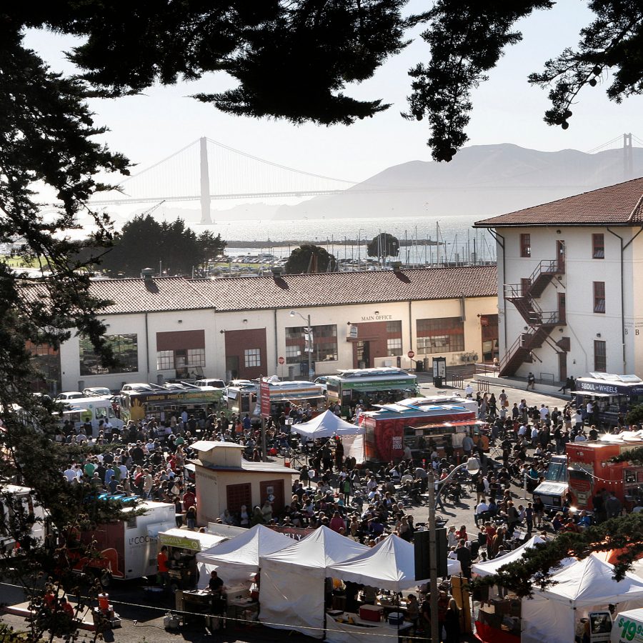A view of Fort Mason Night Market in San Francisco on a sunny day see through a frame of leaves