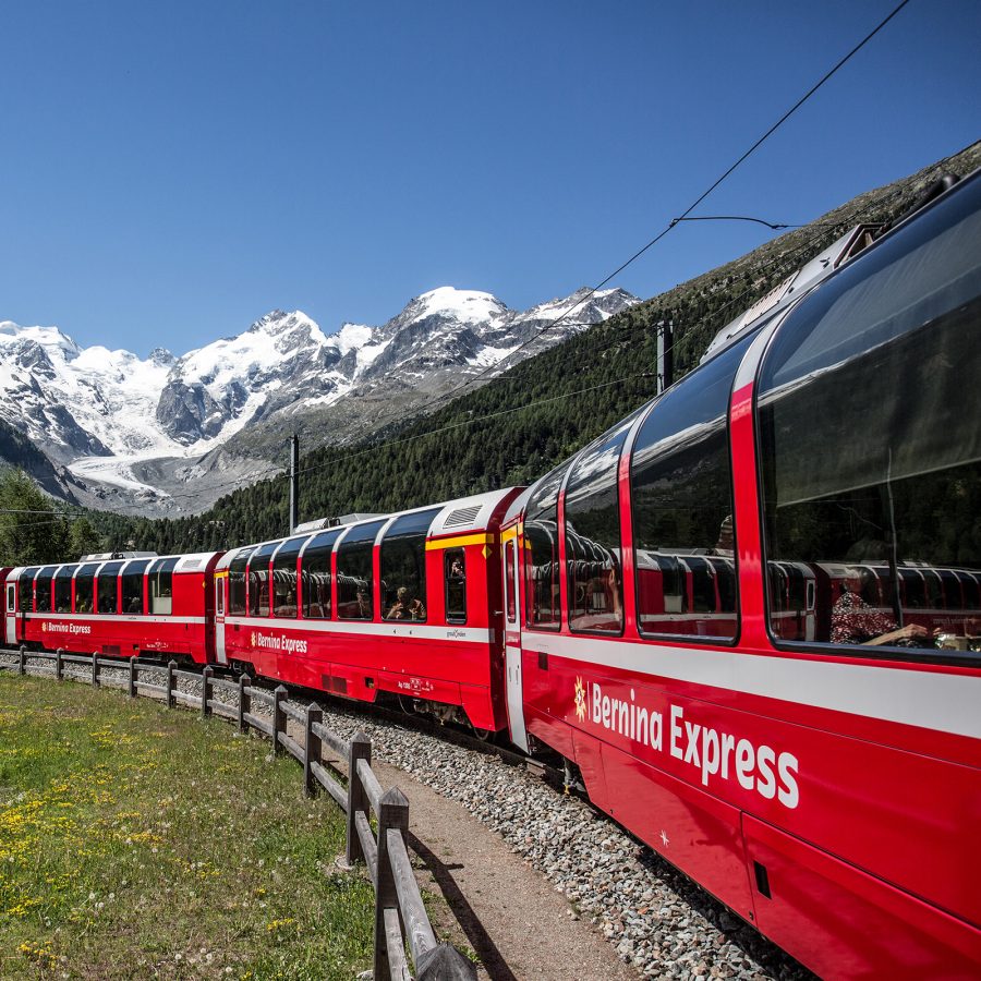 The Bernina Express snakes beneath snowcapped mountains. 