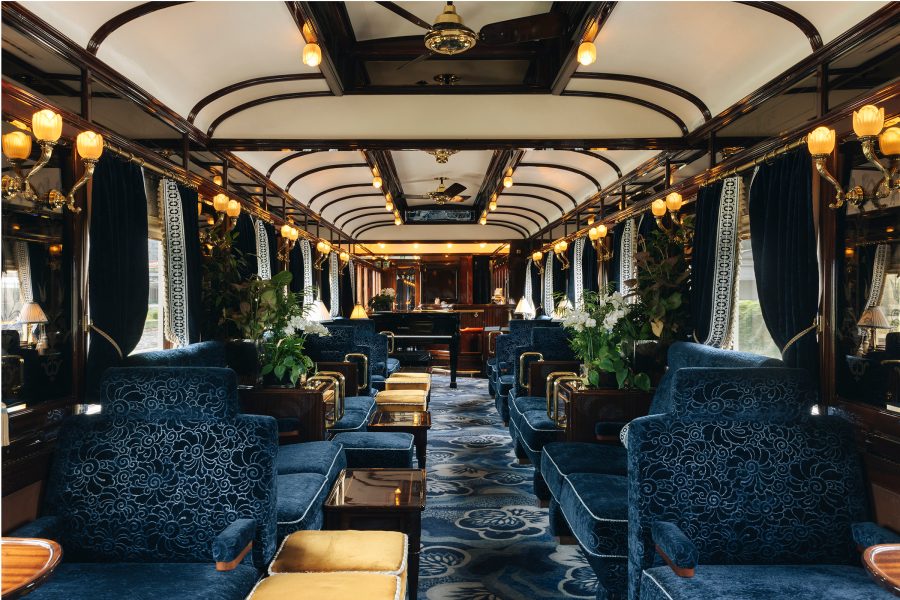 A carriage on the Venice Simplon-Orient-Express is lined with intricately detailed plush seats and wall lights.