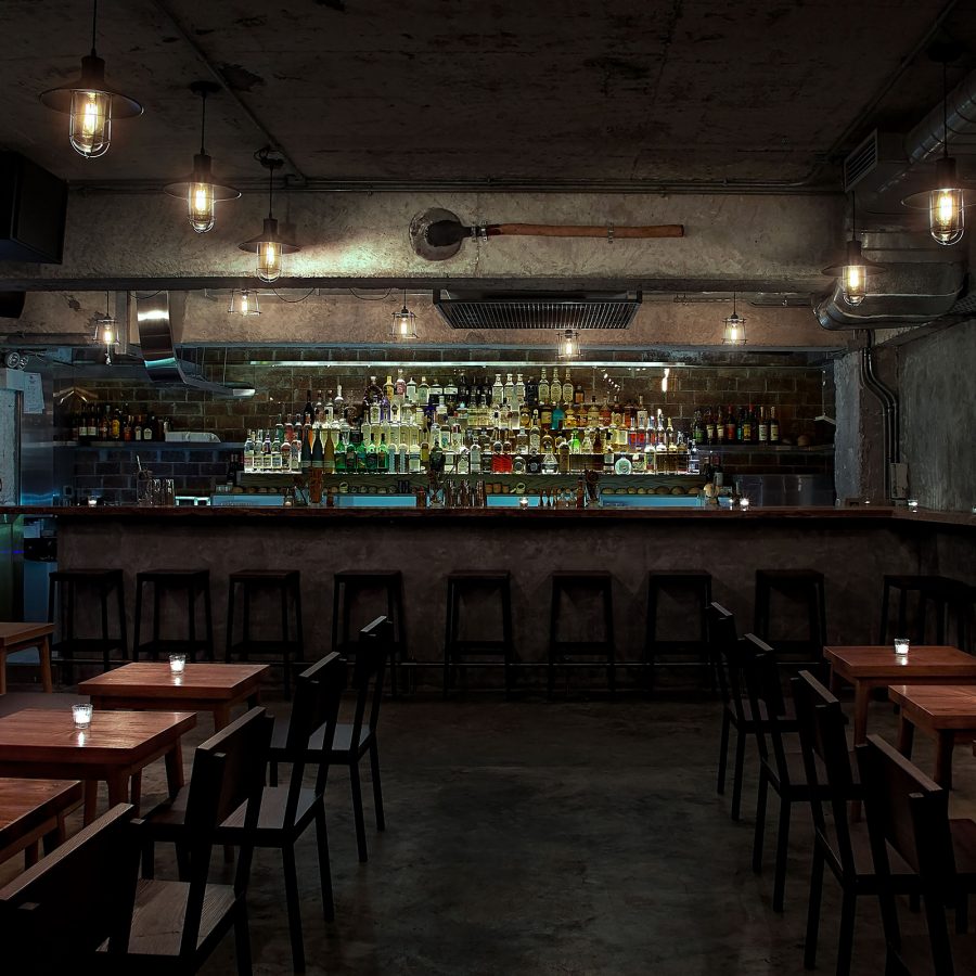 The cosy and intimate interior of COA in Hong Kong, featuring low lighting and low wooden tables.