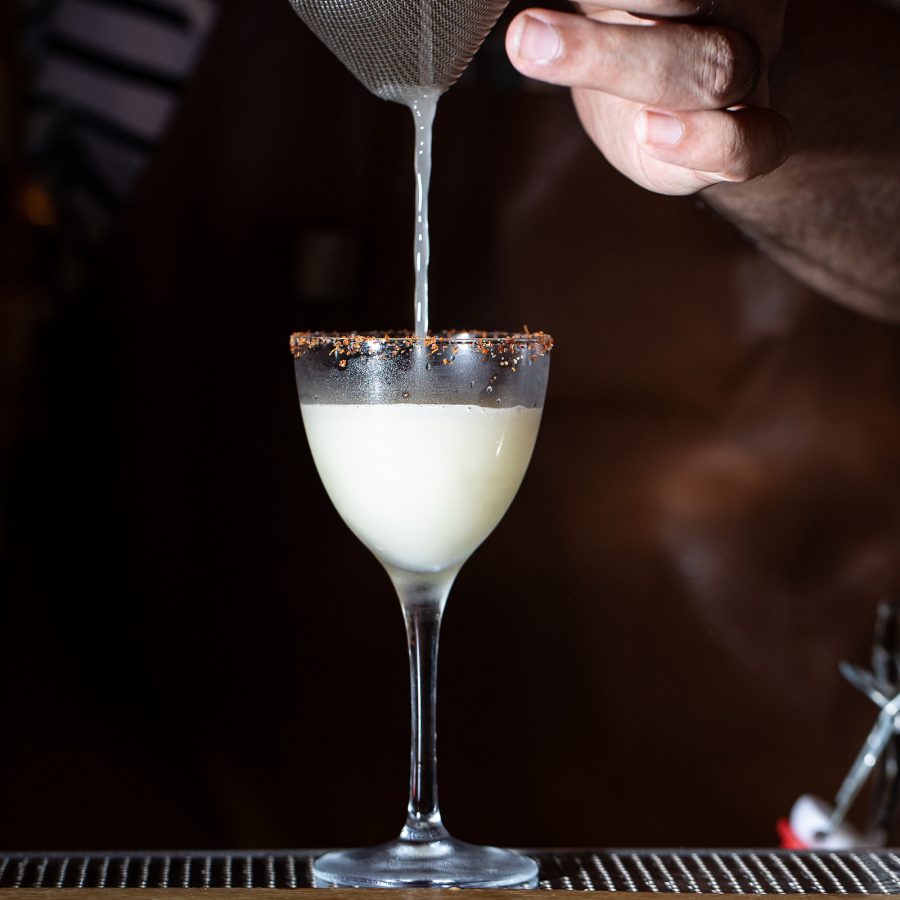 Close-up of a hand pouring liquid into a glass at COA in Hong Kong. 