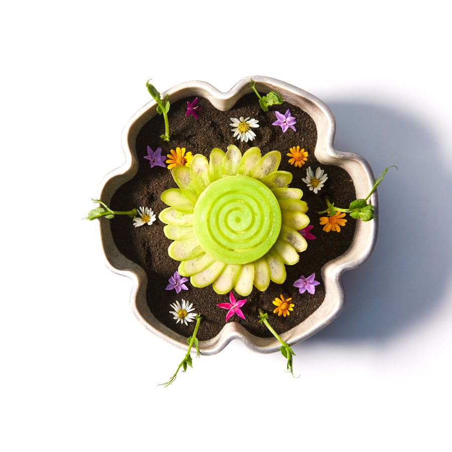 A flat-lay shot of a flower-shaped dish with edible flower garnishes, served at Gaggan in Bangkok, Thailand.