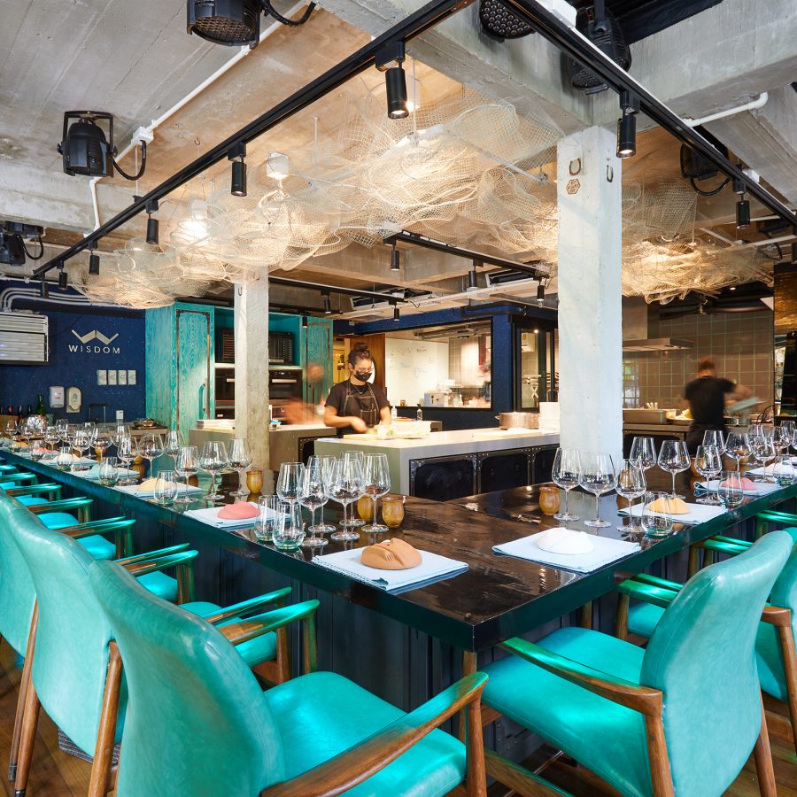 Teal chairs around a counter table at Gaggan in Bangkok, Thailand.