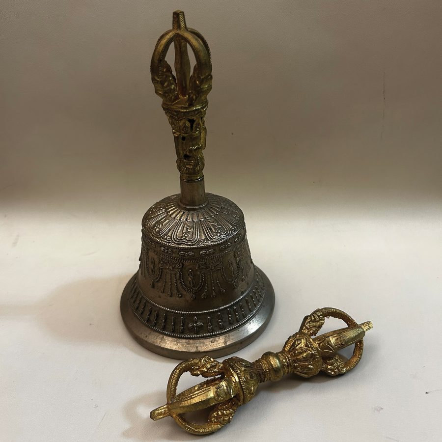 A bell and a type of sceptre called a vajra, both small, metallic and ornately carved