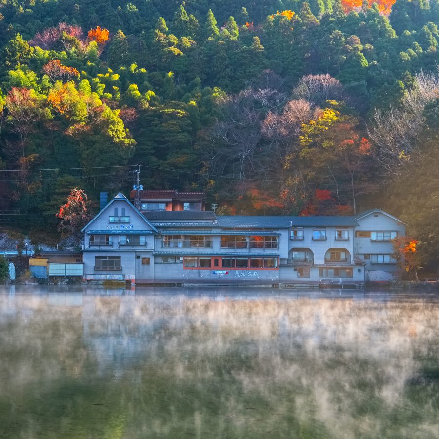 A lake in Yufuin on Kyushu reflects the buildings on the waterside as well as the red autumn leaves.