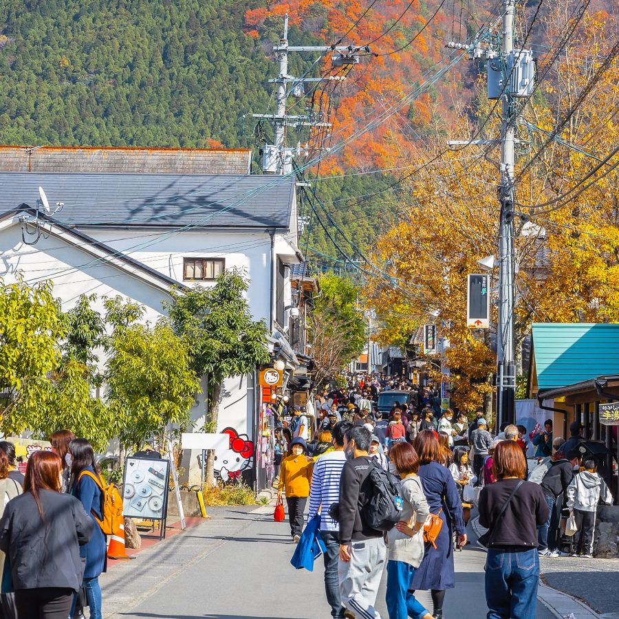 People walk on a street in Yufuin during the autumn, when the hillside starts turning red and gold.