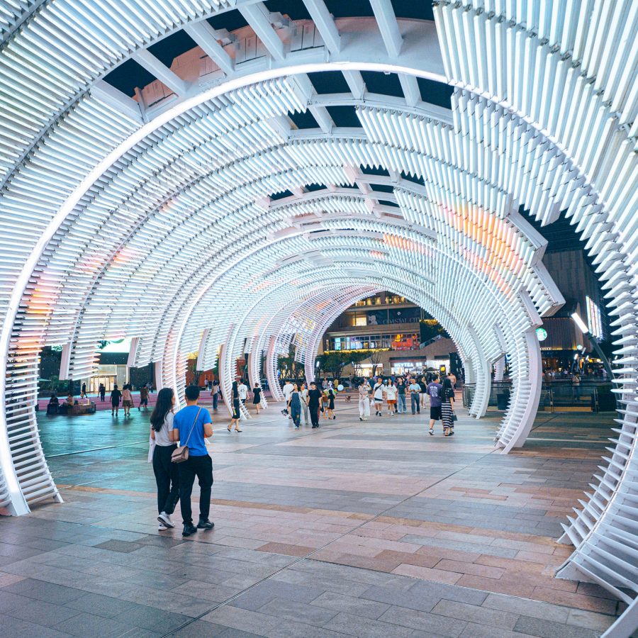 People walking through a light tunnel at Shenzhen’s Coastal City shopping complex at night