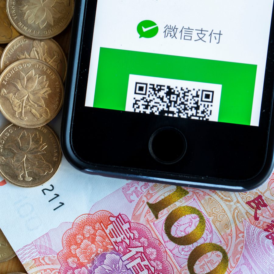 A pile of Chinese coins and a CNY100 note and a smartphone with the WeChat app open