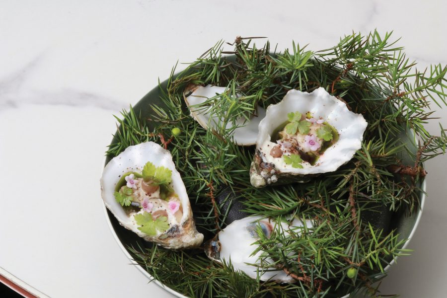 An oyster dish garnished with small flowers and sprigs served at Feuille in Hong Kong.