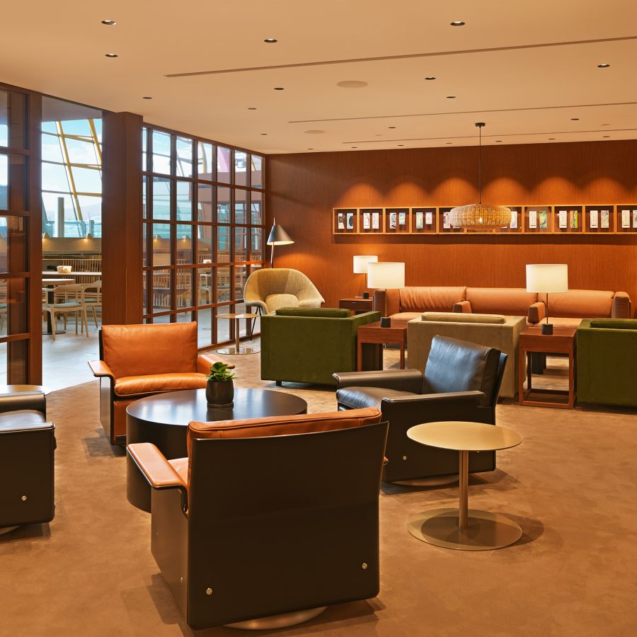 Armchairs and coffee tables at Cathay Pacific’s Beijing lounge. William Lim’s boarding pass drawings hang above a sofa in the background.