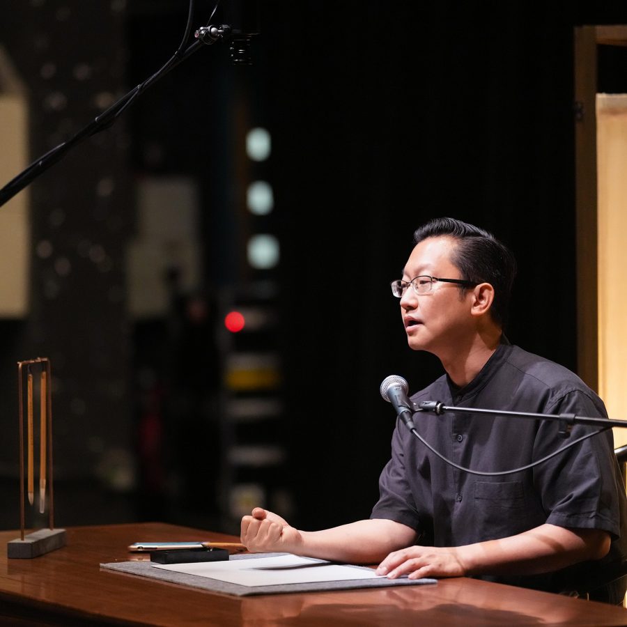 Chui Pui Chee speaking into a microphone while seated at a desk.