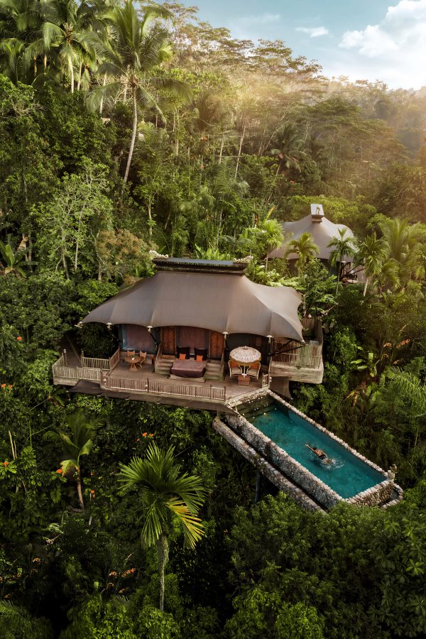 Aerial daytime view of a tented accommodation with an outdoor pool nestled in the forest at Capella Ubud, Bali.