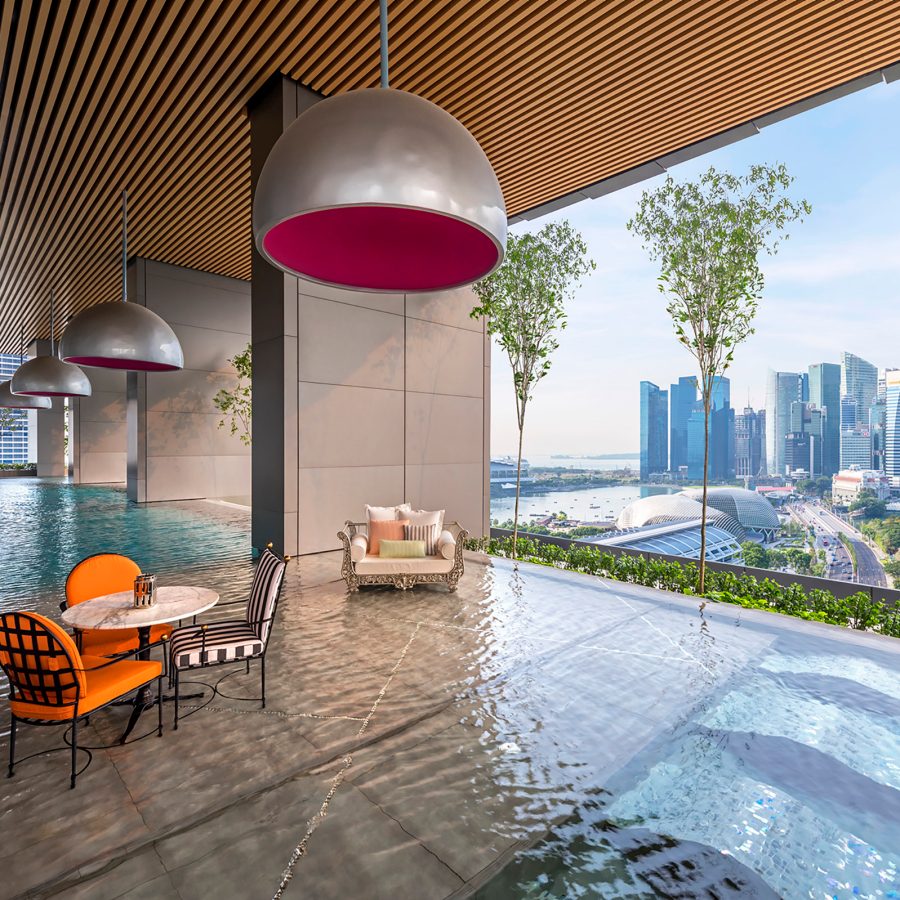 View of the swimming pool at JW Marriott Singapore South Beach and dining tables overlooking the Singapore skyline.