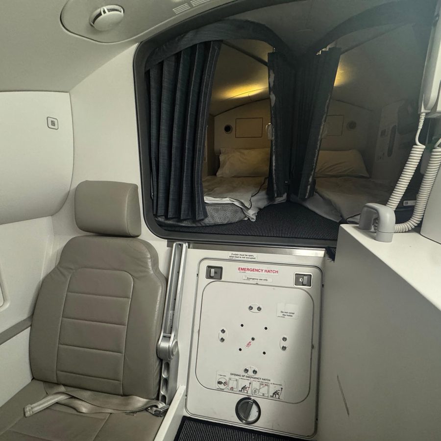 A seat and two bunks separated by a curtain on board Cathay Pacific aircraft.
