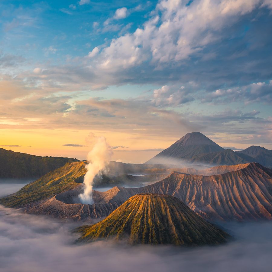 A view of Mount Bromo and neighbouring peaks from above shows them resting above a sea of clouds.   
