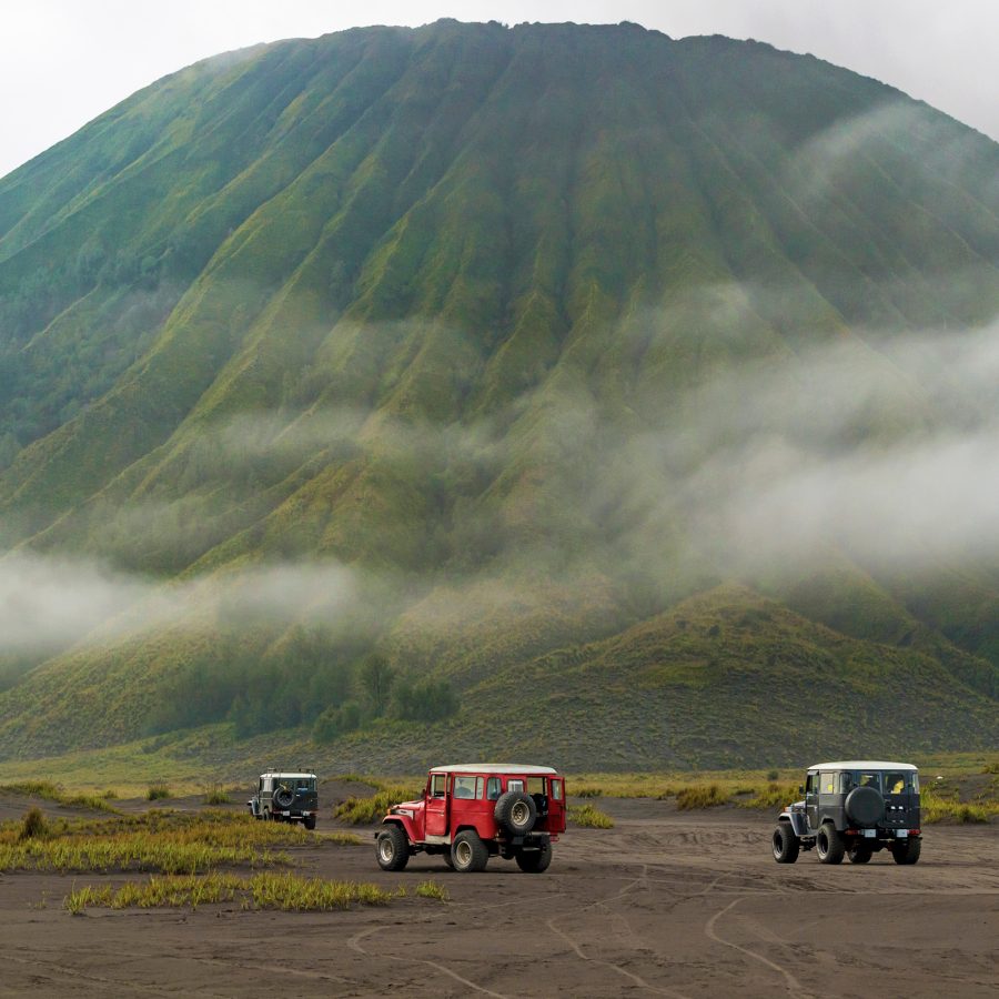 Numerous jeeps crawl across the landscape below Mount Bromo. 