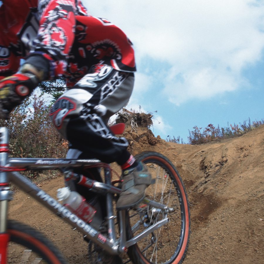 A mountain biker moves down the side of a dirt trail.