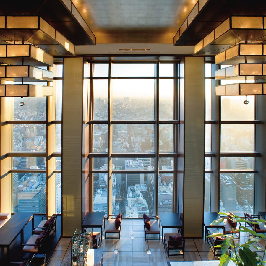 An interior view of the hotel lobby at Mandarin Oriental Tokyo with a view of the city seen through floor-to-ceiling windows 