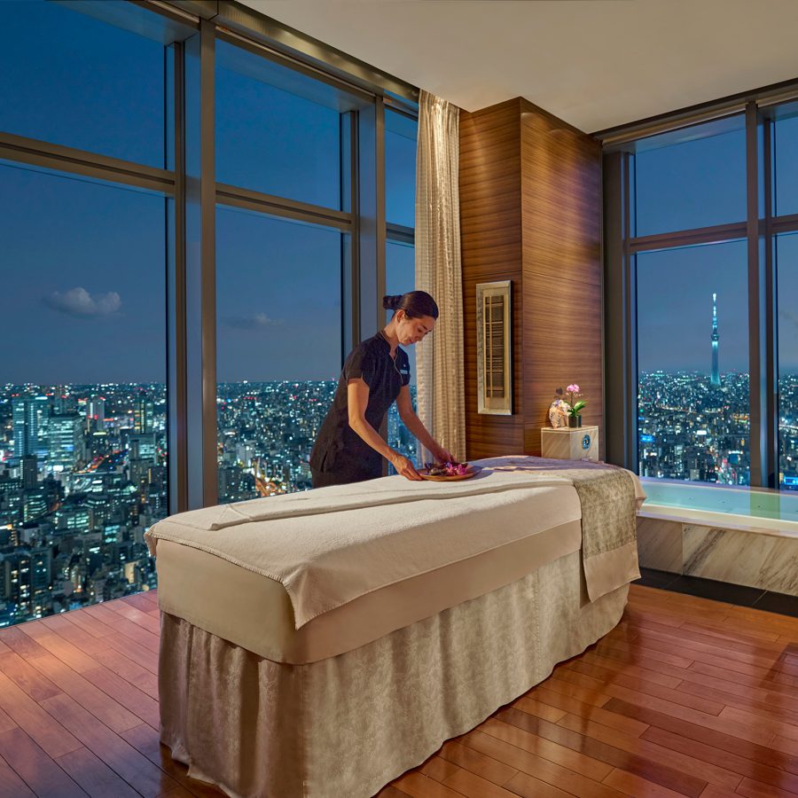 A woman arranges a massage table with a view of the city seen through floor-to-ceiling windows at the Mandarin Oriental Tokyo spa