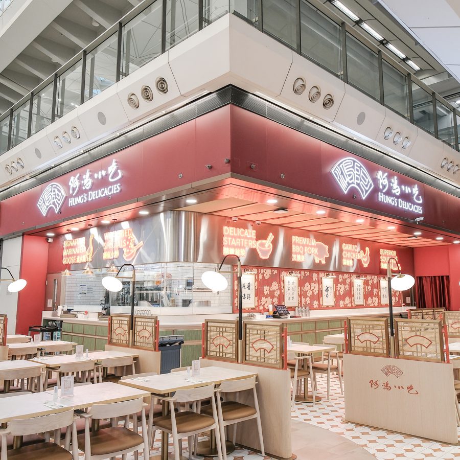 Exterior view of Hung’s Delicacies storefront at Hong Kong International Airport and the white tables around it.