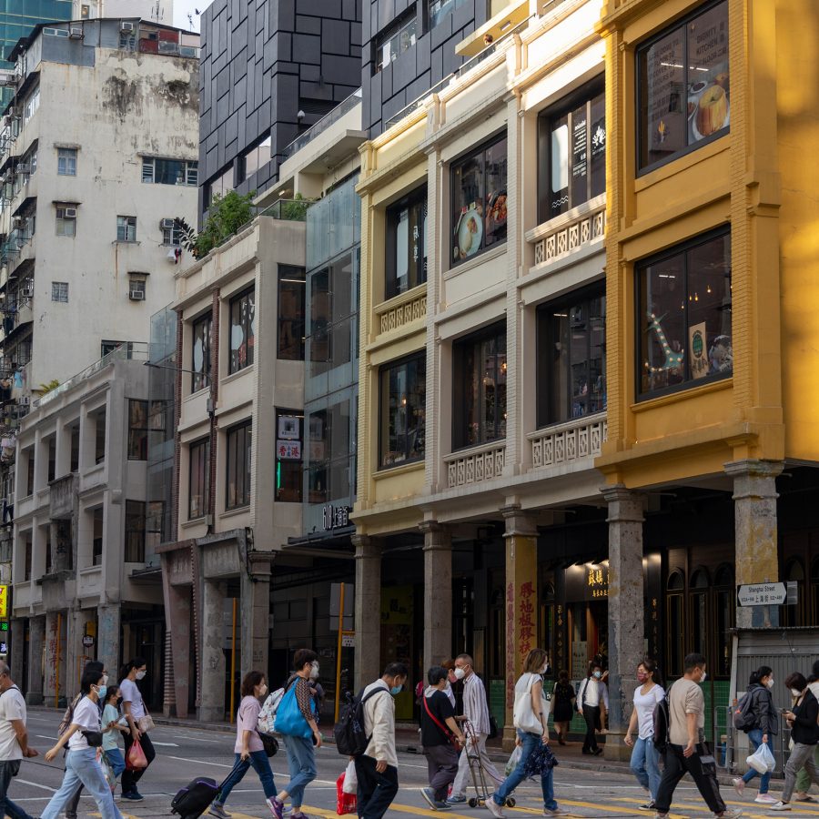 People crossing Shanghai Street in Hong Kong with bags and suitcases.