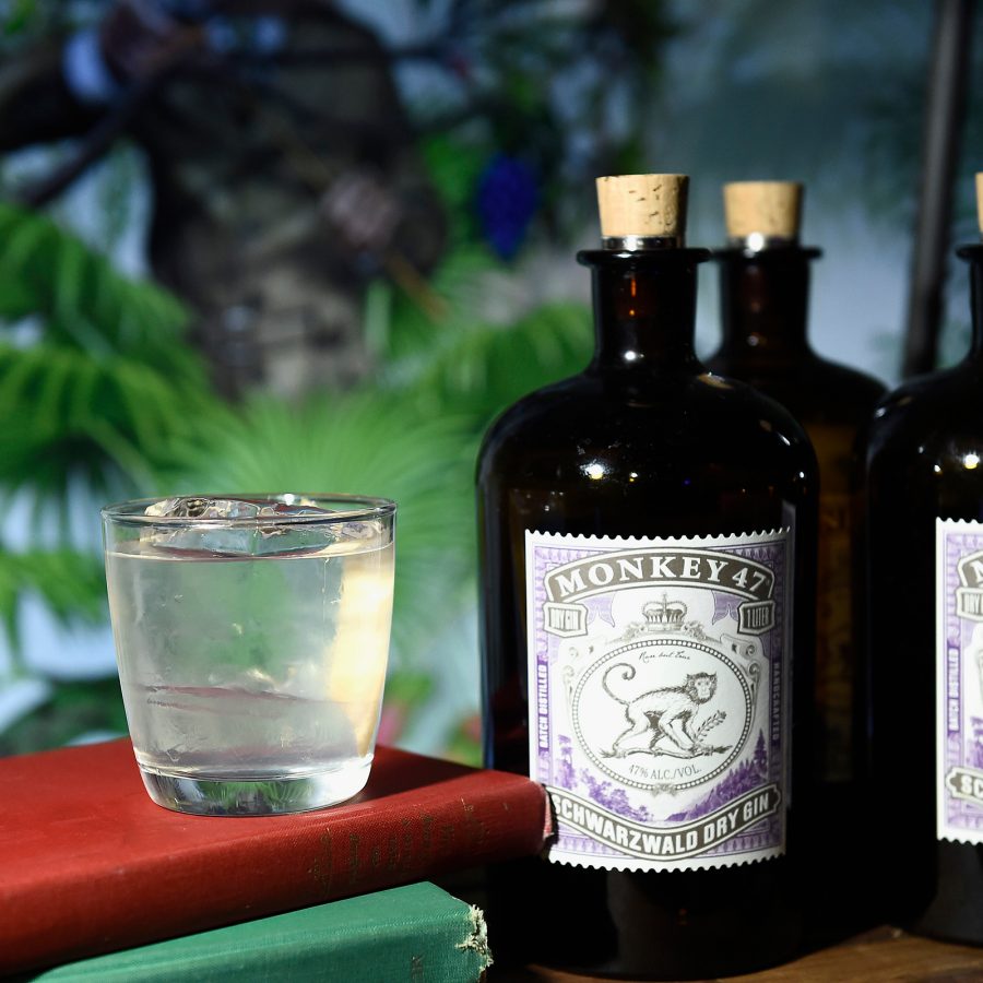 Close up on a number of Monkey 47 gin bottles sitting beside a cocktail glass.