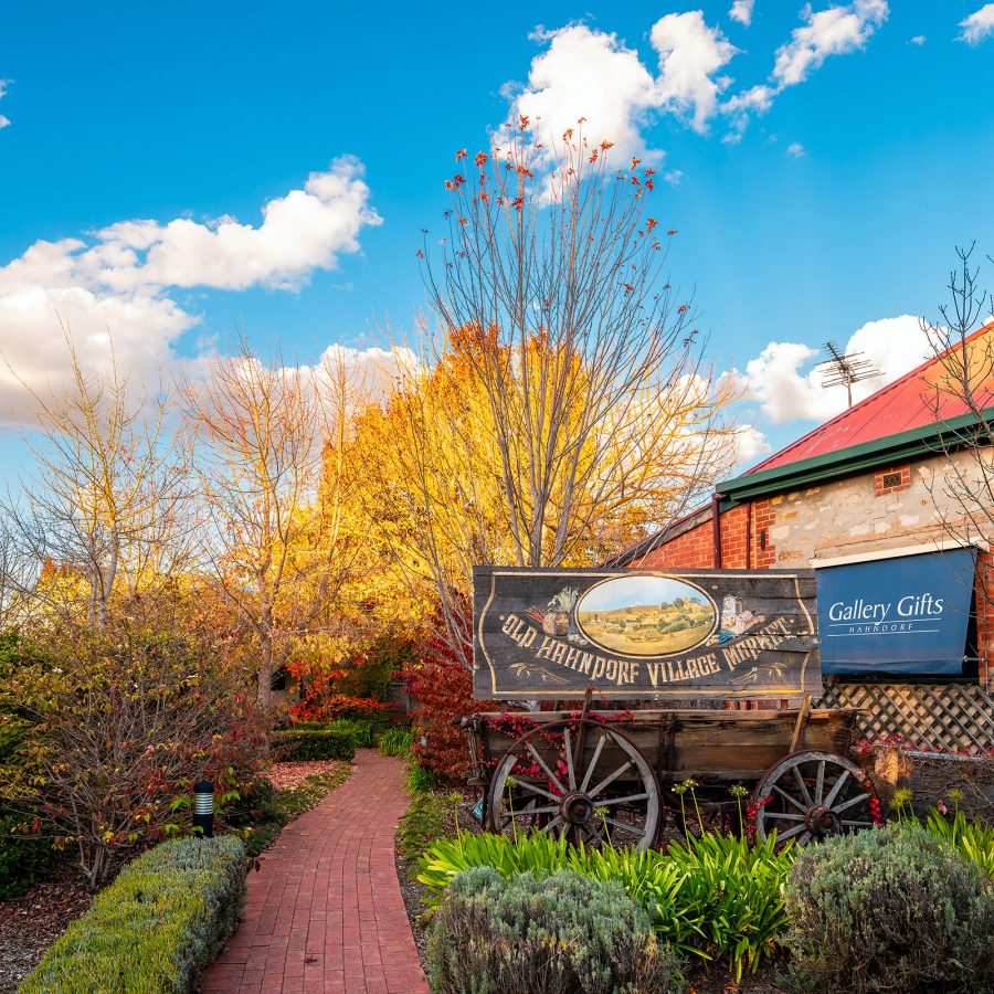 A brick path winds next to a building along a rustic-looking area in Adelaide Hills, as the leaves turn golden. 