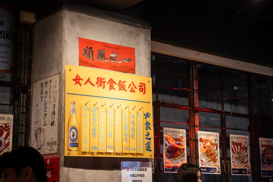 A classic menu board hangs from a concrete pillar at Ladies Street Sik Faan Co.