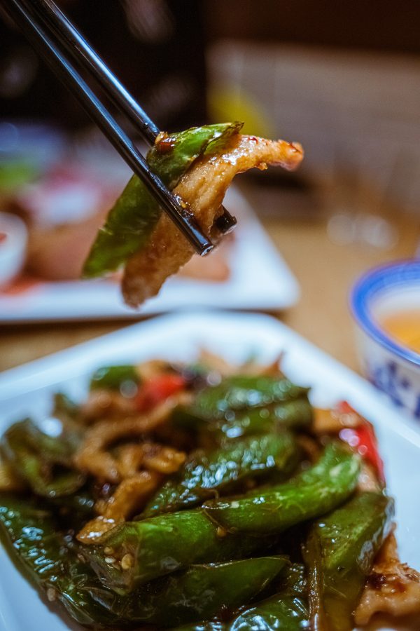 A diner picks up a green pepper and pork jowl from a dish at Mui Kee.