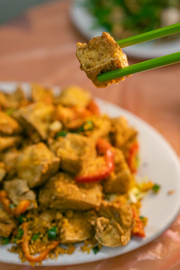 A diner picks up a fried tofu from a dish at Oi Man Sang. 