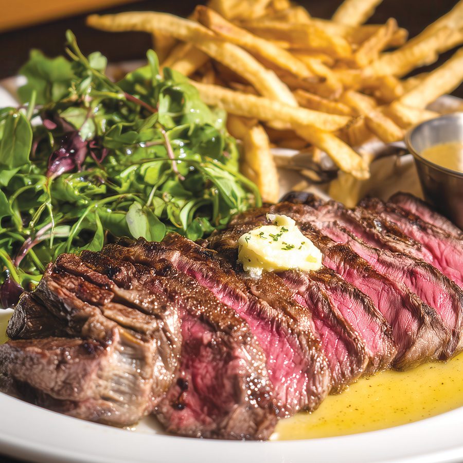 Closeup of a plate of steak and fries with salad and gravy on the side, served at Flat Iron Steak in Hong Kong