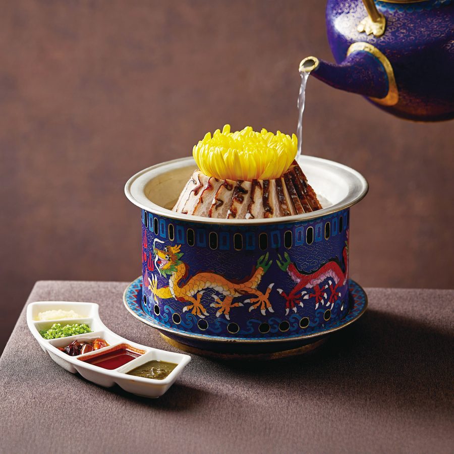 A person pours a liquid from a teapot into a deep dish at Jing Hua Lou.