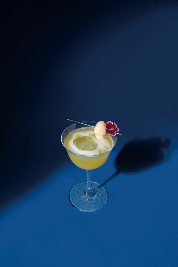 A cocktail stands against a blue background.