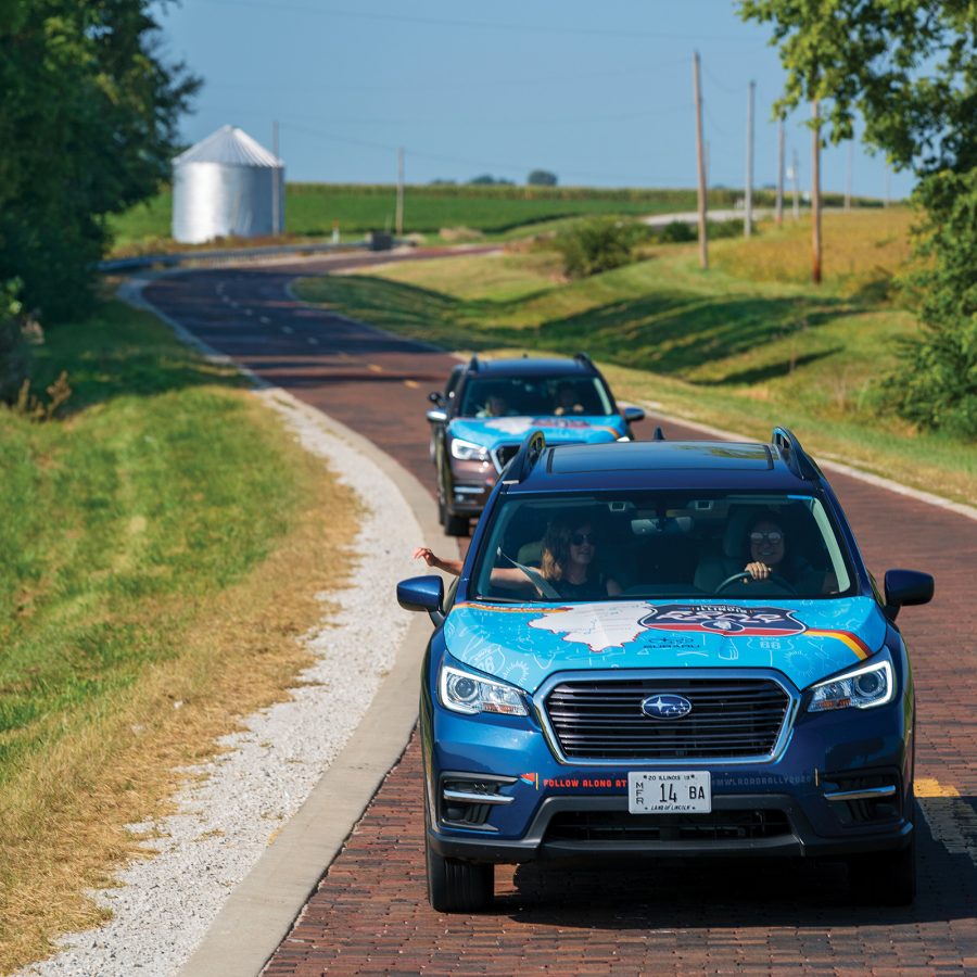 Two blue cars on a road on Route 66.