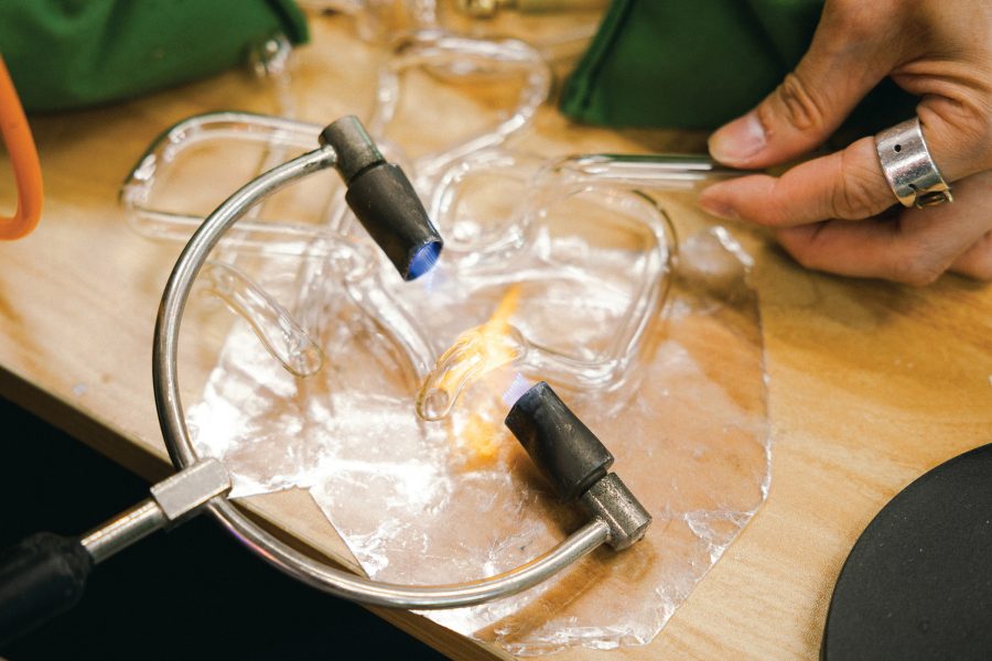 A hand holds a piece of glass tube while it’s being melted and shaped