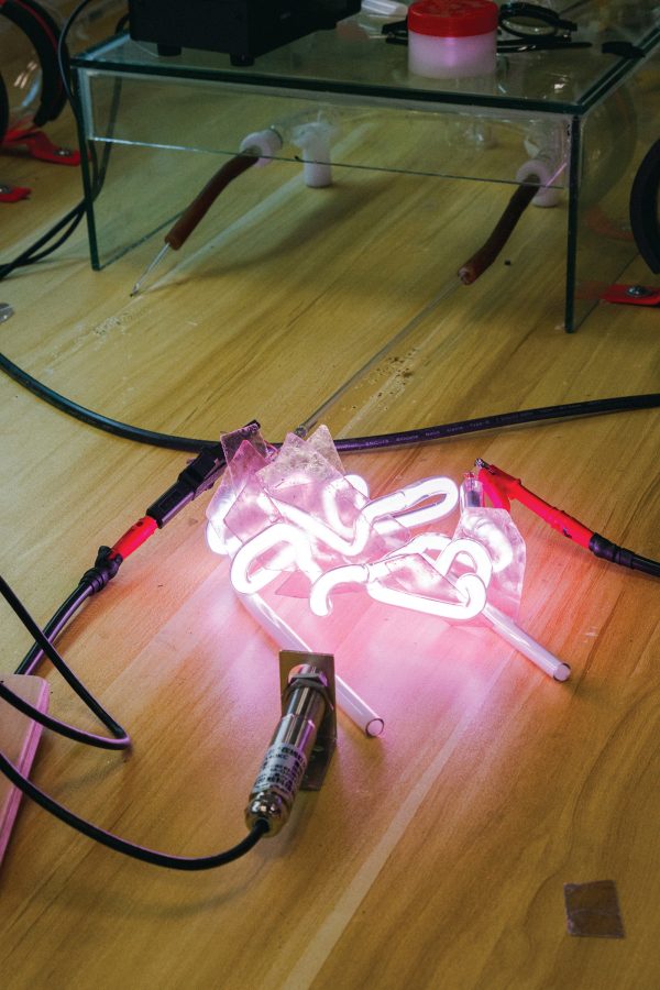 A red neon sign design glowing on a wooden floor