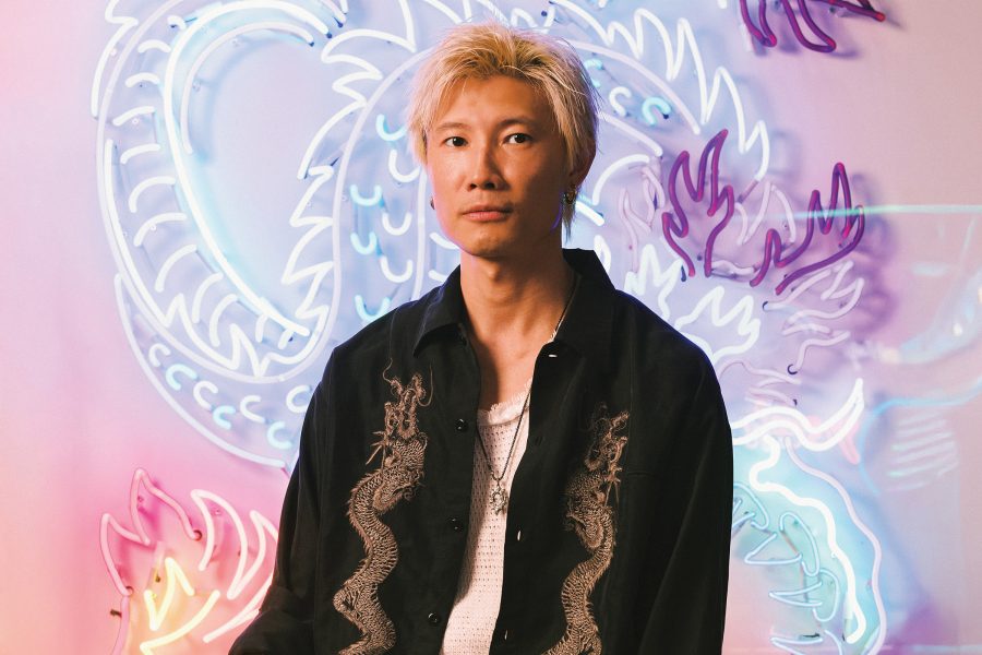 Jive Lau, Hong Kong neon light artisan and founder of Kowloneon, sits infront of an original purple neon dragon design