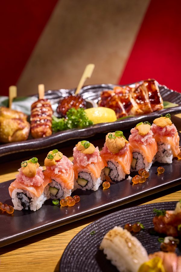 Sushi rolls piled high with salmon and minced tuna are plated alongside skewers at Fumi Joe.