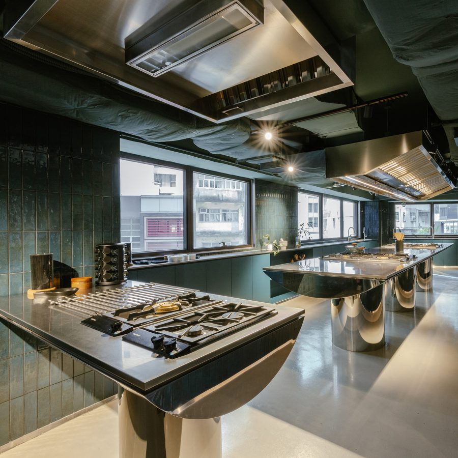 The interior of Solstice has green-grey walls and high tables with cooking appliances installed. 