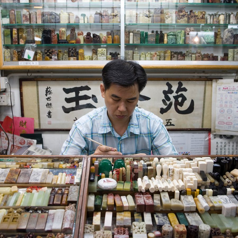 A traditional Chinese chop maker at work behind a stall at Chop Alley in Sheng Wan, Hong Kong