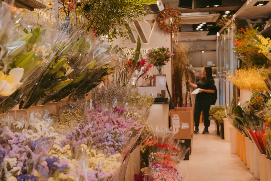 A view inside a flower shop featuring various flowers and a woman browsing at Flower Market in Prince Edward, Hong Kong