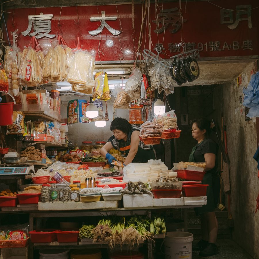 A street view of a shop keeper selling dried beancurd, tofu and vegetables at a market stall in Chun Yueng Street in North Point, Hong Kong