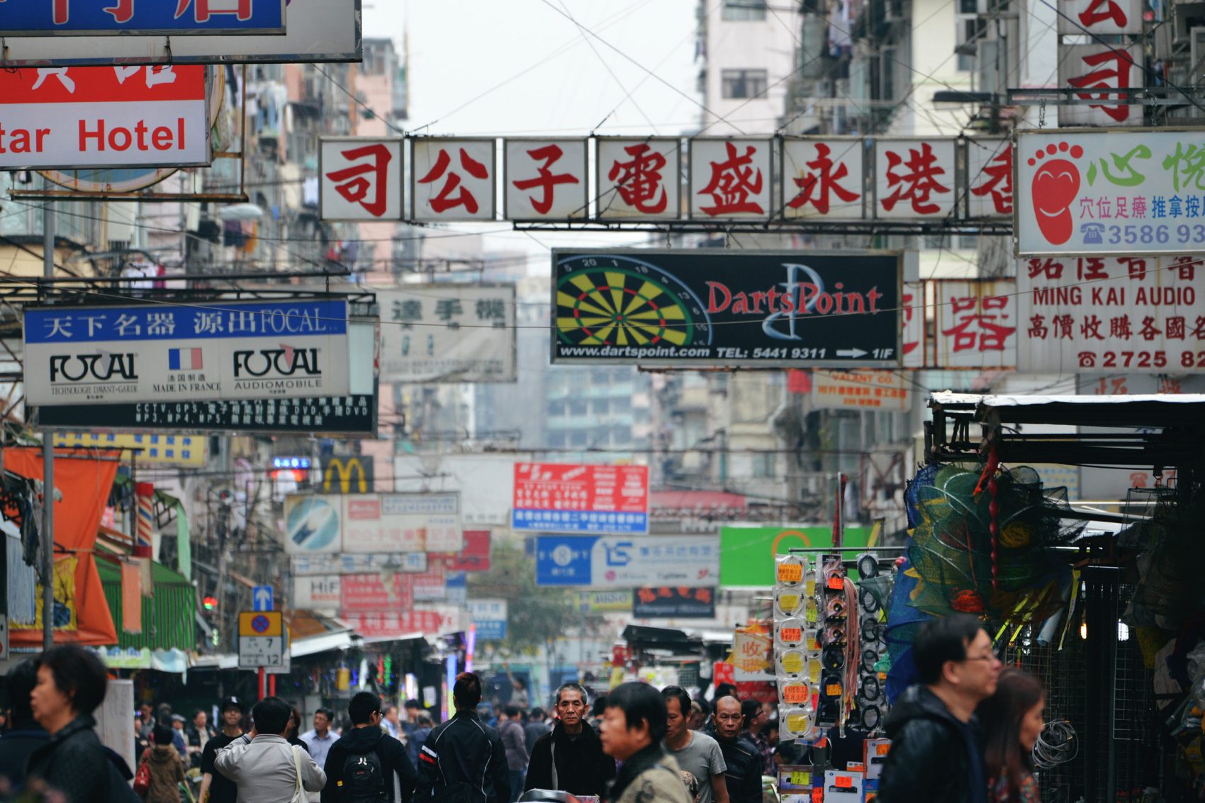 Một góc nhìn về các biển hiệu truyền thống của Hồng Kông treo trên các tòa nhà dọc theo chợ Apliu Street khi đám đông người đi ngang qua ở Sham Shui Po, Hồng Kông