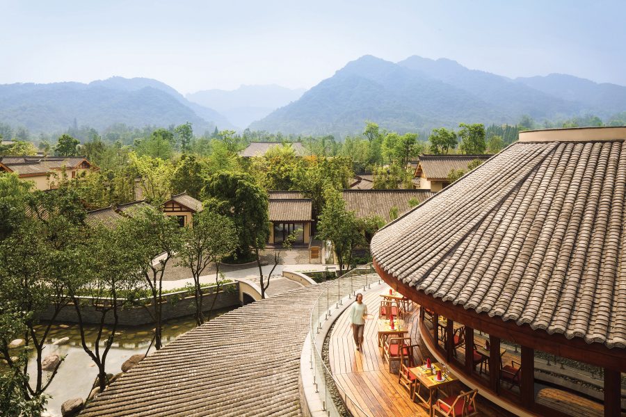 An exterior view of Mandai Rainforest Resort by Banyan Tree in Singapore with views of lush green trees and mountains in the backdrop on a bright day