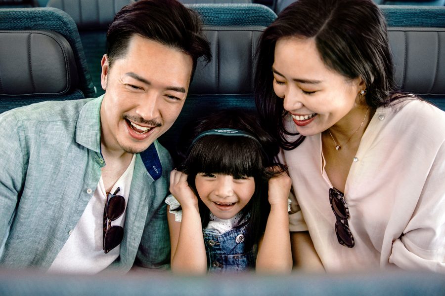 Family sat on a Cathay Pacific flight watching the inflight entertainment 