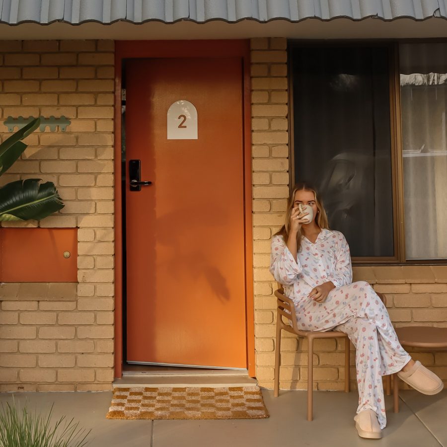 A woman enjoys a cup of coffee outside a room at The Timothée Resort, Busselton. 