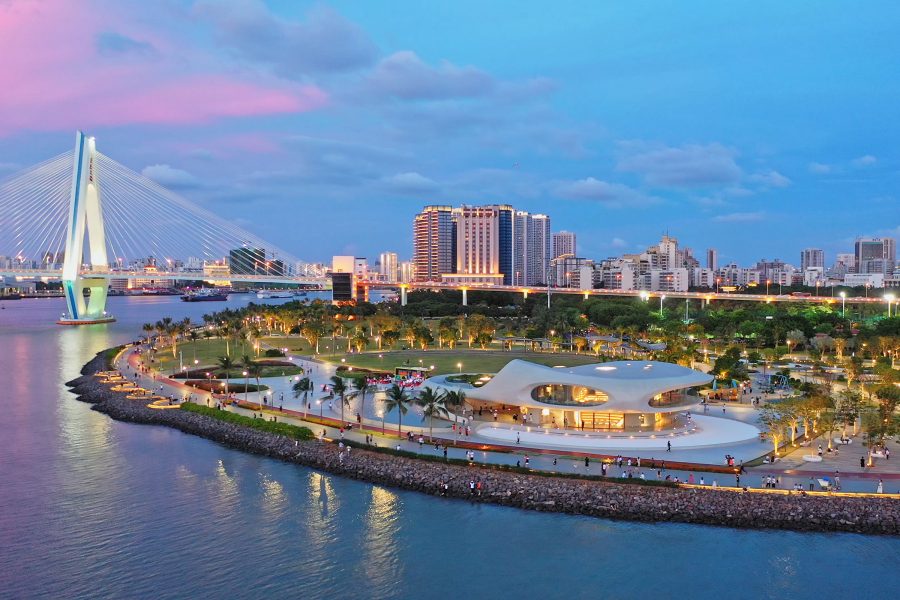 View of the skyline in Haikou with a bridge and illuminated park on the waterfront.
