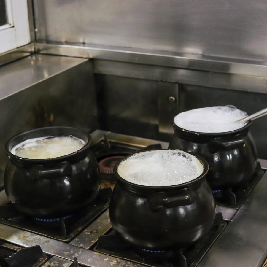 Three claypots of congee on a stove.