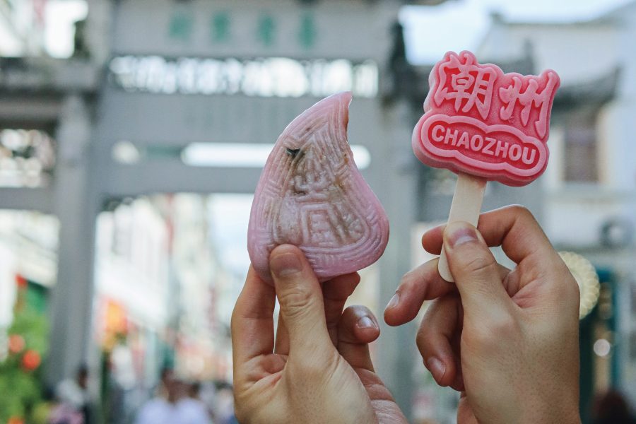 Hands holding up a pink dumpling and a red lolly with “Chaozhou” imprinted on it.